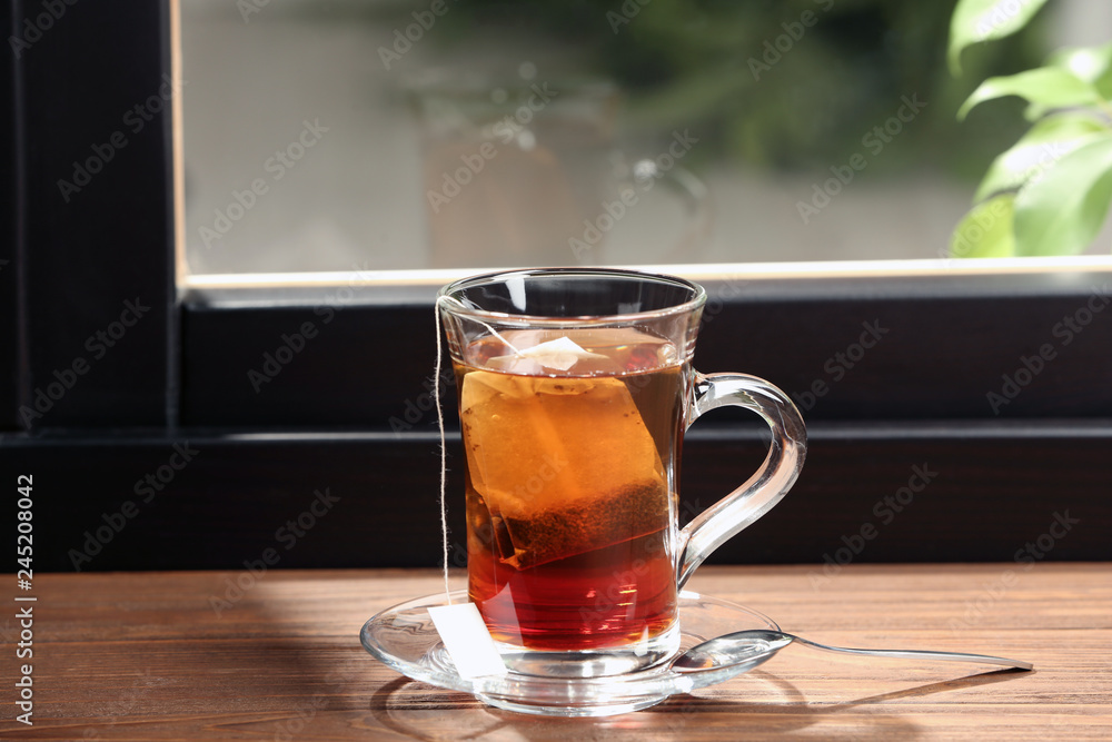 Glass cup of hot tea on wooden window sill Glass cup of hot tea on wooden window sill