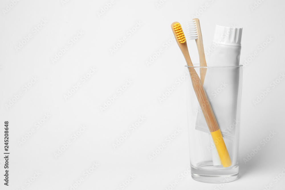 Glass with brushes and toothpaste on white background. Space for text Glass with brushes and toothpaste on white background. Space for text