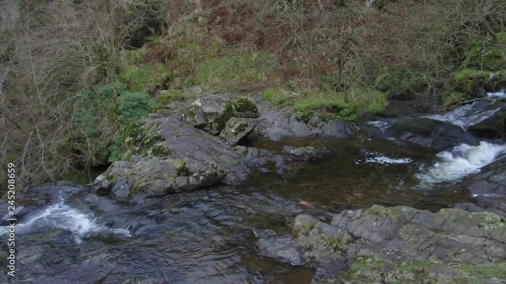 Waterfall in a little glen flowing over rocks and surrounded by trees. Waterfall in a little glen flowing over rocks and surrounded by trees.