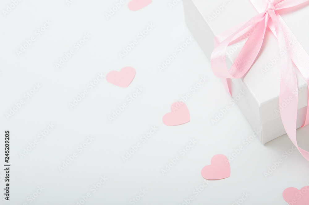 White gift box with pink ribbon and hearts on a white background. Valentine's day gift, women's day. Copy space