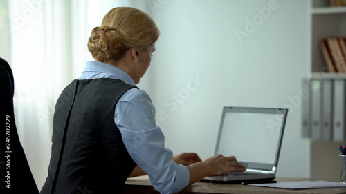 Photos Female secretary typing on laptop in office, busy working schedule, back view