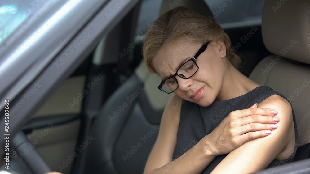 Lady suffering from shoulder pain while sitting in car, joint inflammation Lady suffering from shoulder pain while sitting in car, joint inflammation