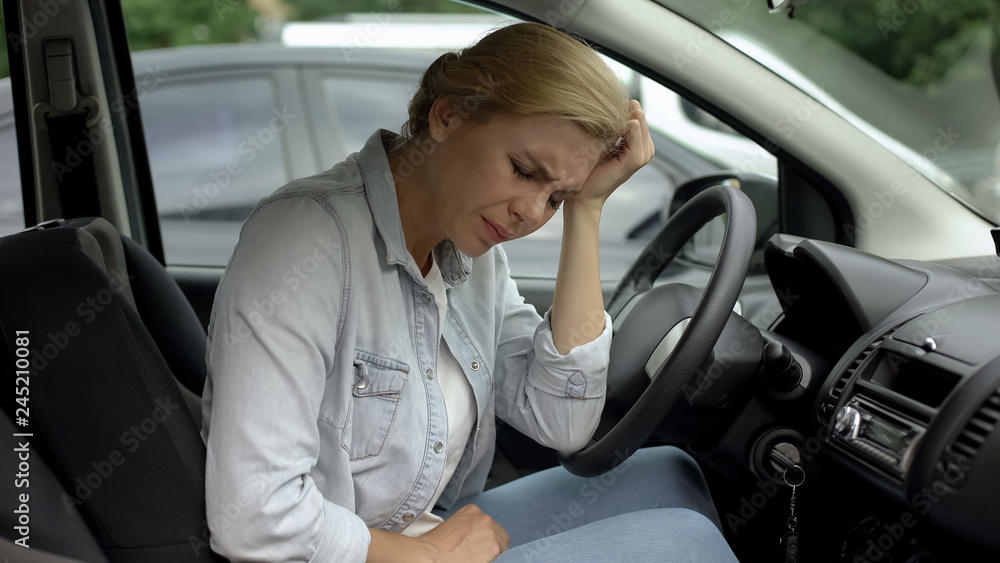 Upset female suffering from headache, sitting in automobile, migraine, health Upset female suffering from headache, sitting in automobile, migraine, health