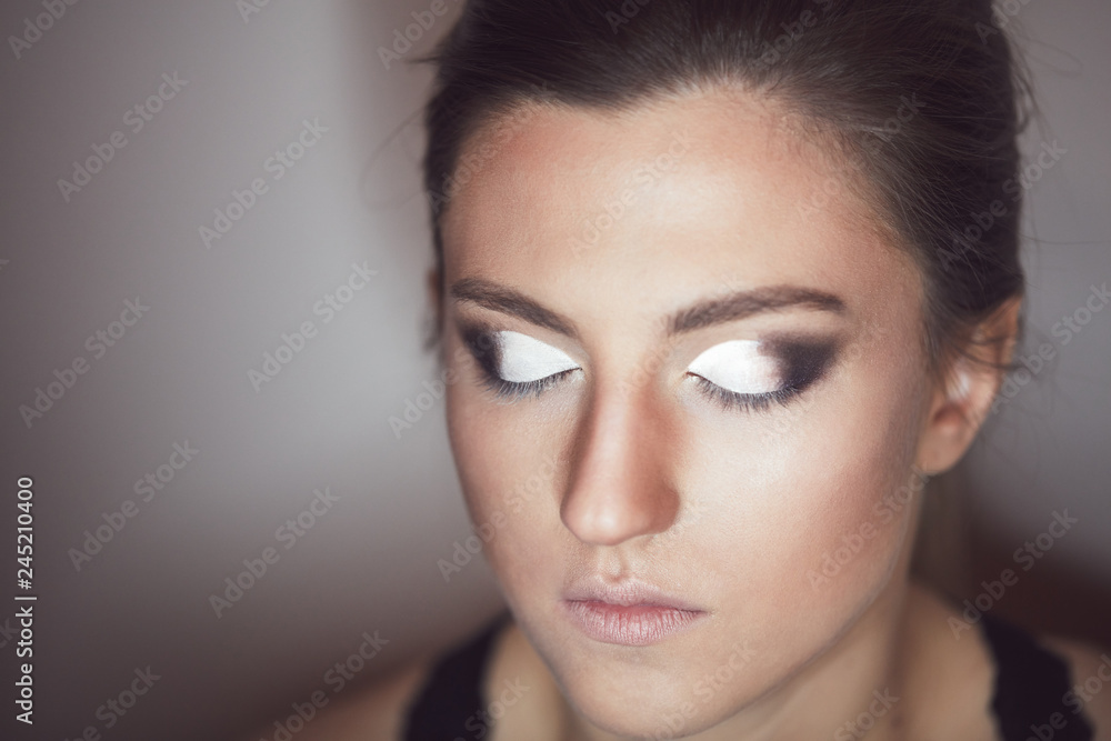 Naklejka premium Young beautiful woman applying make-up by make-up artist. Process of making makeup.