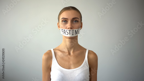 Fasting word written on taped mouth of upset anorexic model, self-destruction