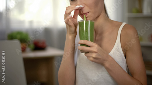 Fotografija Woman drinking disgusting green smoothie, closing nose, bad smell and taste