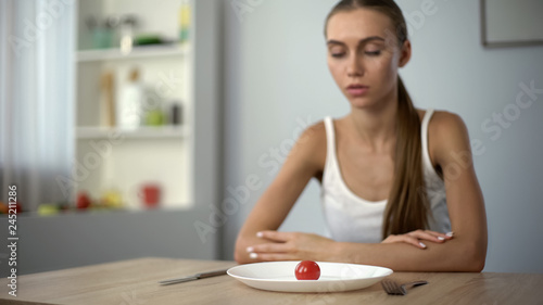 Underweight woman looking at small portion of meal, exhausted body, severe diets photo