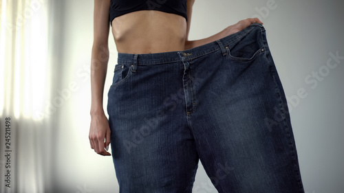 Obraz na płótnie Anorexic girl wearing one trouser-leg, fat people vs skinny, rapid weight loss