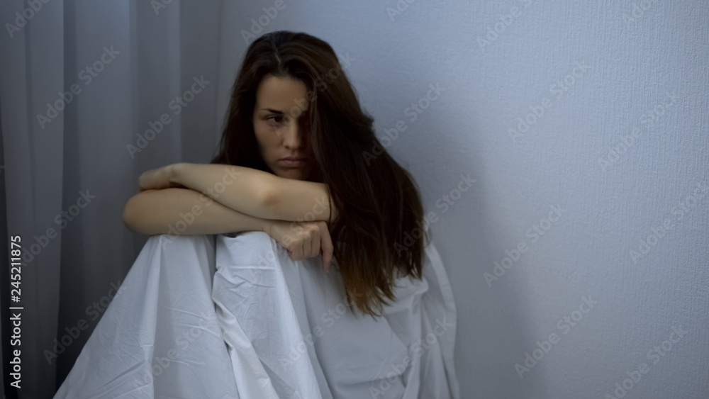 Sad woman with mental illness sitting on floor, hospital patient, depression Sad woman with mental illness sitting on floor, hospital patient, depression
