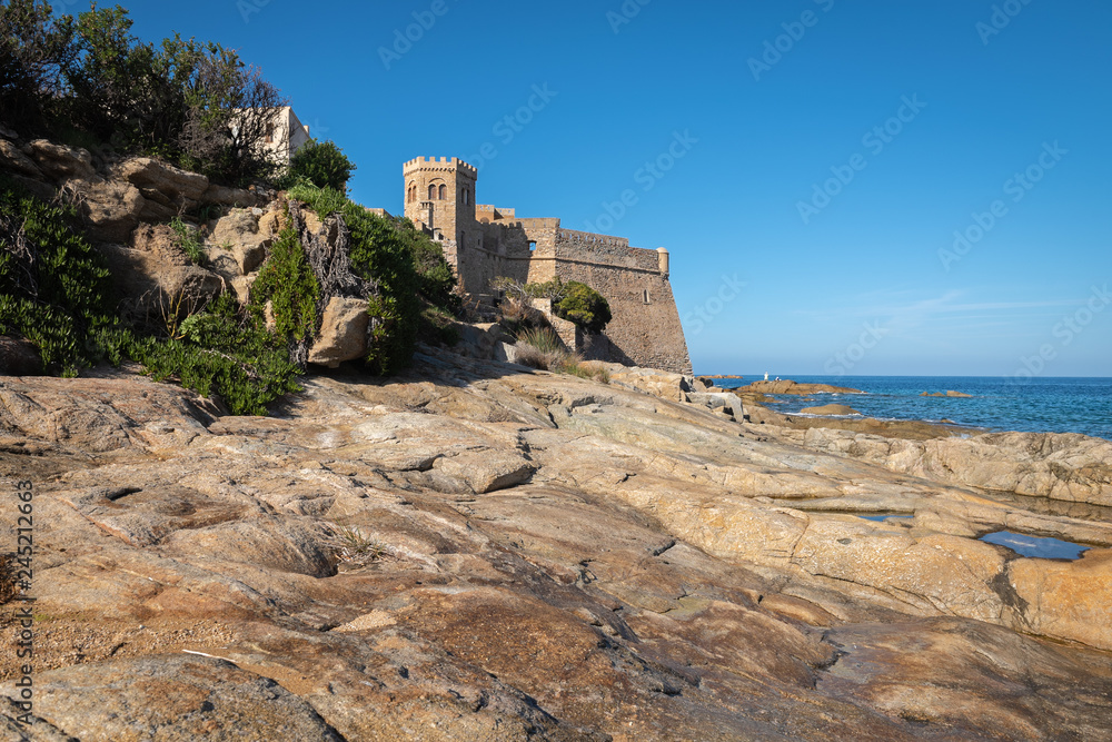 View of the Corsican fortress in Algajola village from the rocky beach, France