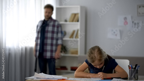 Father holding strap going to child, daughter doing homework, punishment