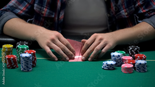 Male casino player checking his card combination in poker game tournament