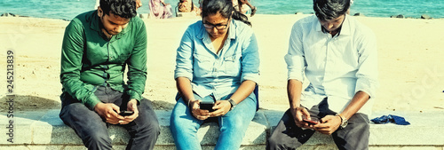 Canvas Print Two men one woman taking selfies at the beach with sea in background