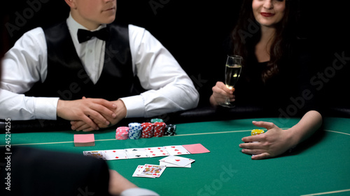 Woman drinking champagne wins poker game at elite casino, upper class gambling