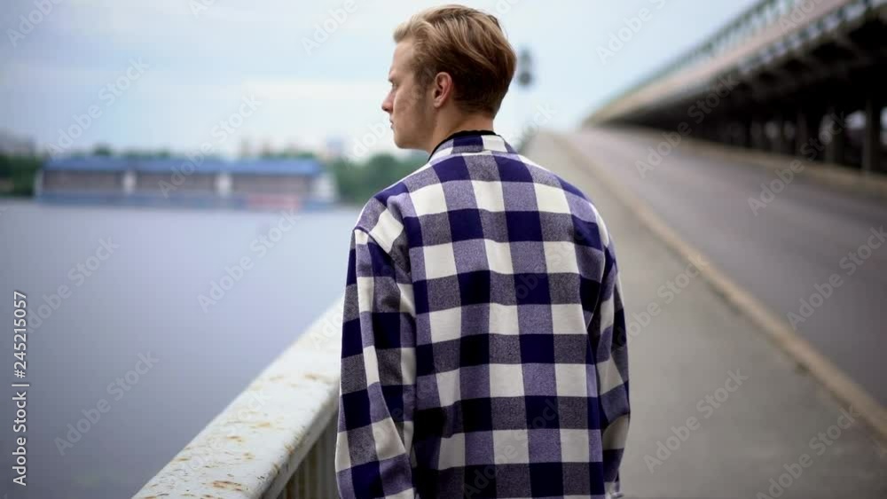young man walking along bridge young man walking along bridge