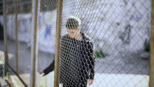 Teen boy behind fence confinement, boarding school restrictions, broken future