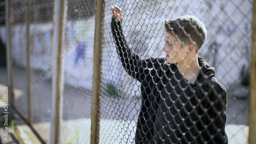 Slika na platnu Boarding school restrictions, teen boy behind fence confinement, broken future