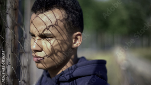 Canvas-taulu Afro-american boy watching rich district through fence, poverty, immigration
