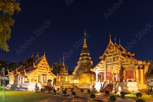 Chapel and golden pagoda at Wat Phra Singh Woramahawihan in Chiang Mai at twilight or night with stars in sky