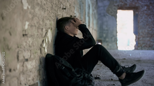 Photography Depressed teen hiding from bullying in abandoned house, difficult adolescence