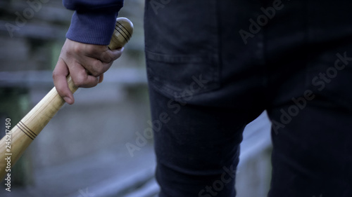 Photography Vandalism, young man walking on stadium tribune with baseball bat, youth gang