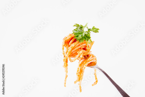 Spaghetti with pesto rosso on a fork decorated with parsley on a white background