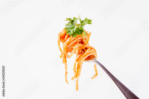 Spaghetti with pesto rosso on a fork decorated with parsley on a white background
