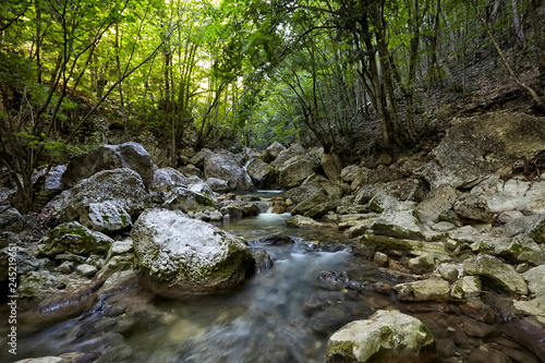 Beautiful waterfall in autumn forest in crimean mountains. Stones with moss in the water. Blurred water.