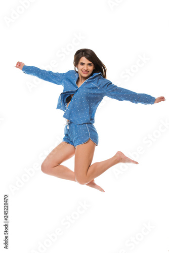 Happy young woman in pajamas jumping isolated on white background