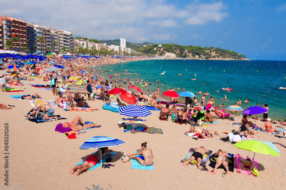 Tourists on sandy sea beach in Lloret de Mar, Spain