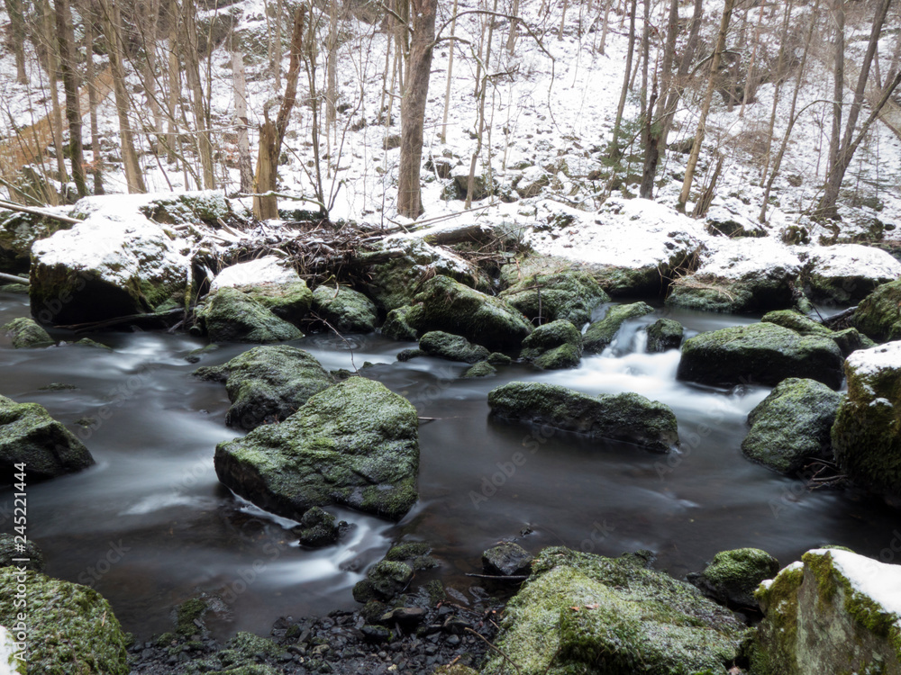 smooth motion of wild water in a river in winter with snow and ice on rocks and stones in the beautiful nature of a forest smooth motion of wild water in a river in winter with snow and ice on rocks and stones in the beautiful nature of a forest
