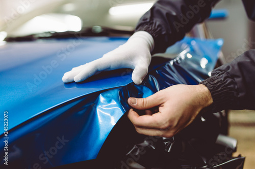 Car wrapping specialist putting vinyl foil or film on car. Selective focus. photo