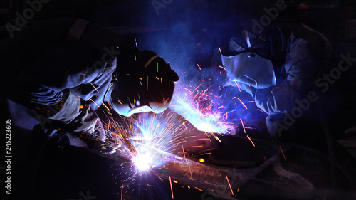 Welders welding metalwork in a factory