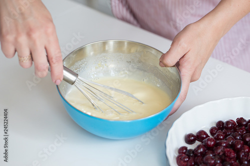 Young woman cooking in kitchen.Clafoutis cherry pie photo