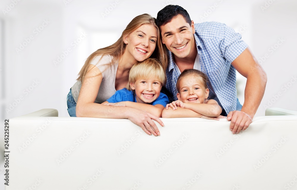 Beautiful smiling family sitting at sofa on background Beautiful smiling family sitting at sofa on background