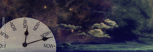 Time is only ever NOW day or night - white clock face with NOW replacing the numerals against a cloudy dark night sky background  photo