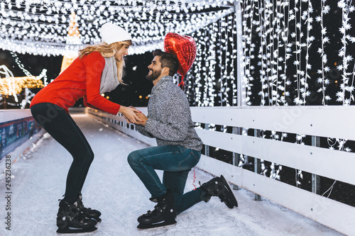Handsome man proposing a beautiful woman to marry him in ice skating rink.
