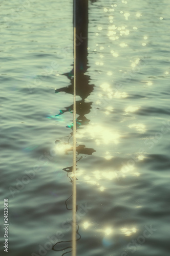 Rope over the water with bright golden reflections and bokeh background blur. © DR pics