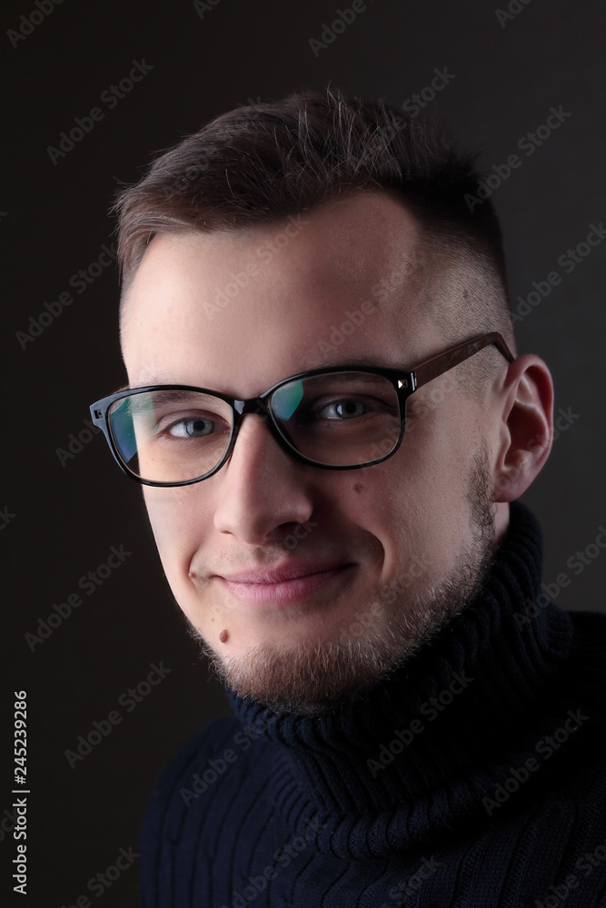 Young man in eyeglasses close up portrait, on black background.Emotion. Smile Young man in eyeglasses close up portrait, on black background.Emotion. Smile