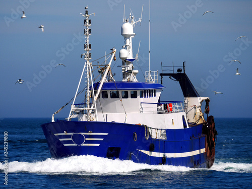 Fishing vessel underway at speed to discharge fish at market.