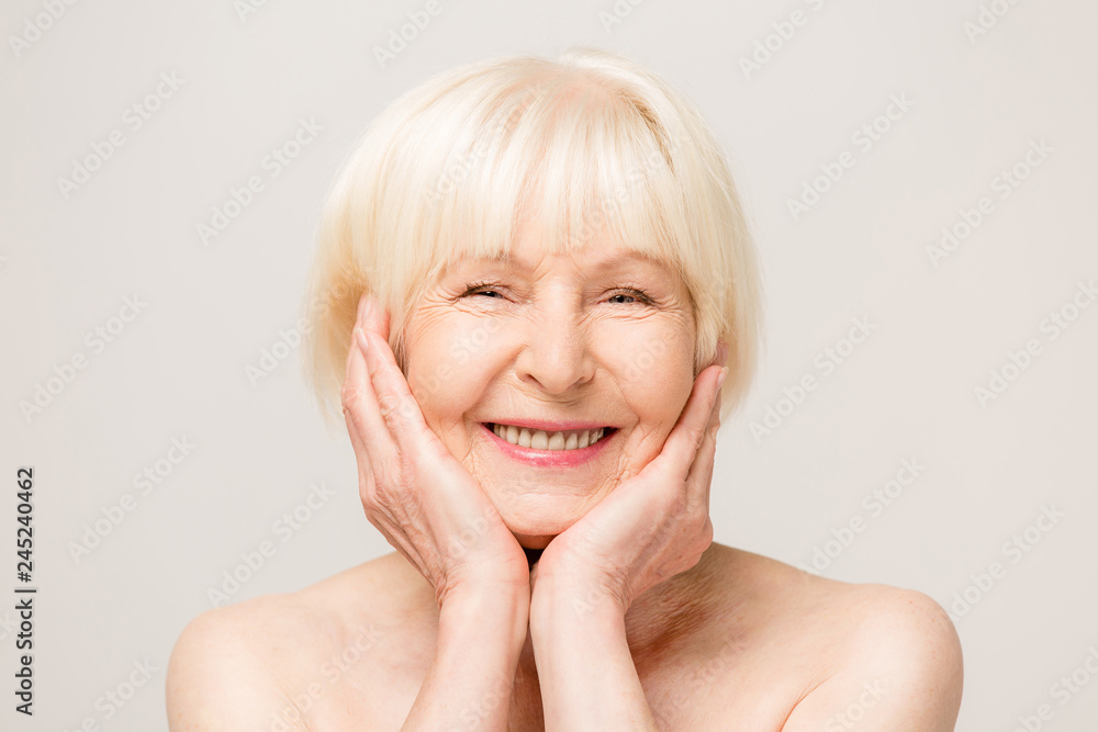 Charming, pretty, old woman touching her perfect soft face skin with ...