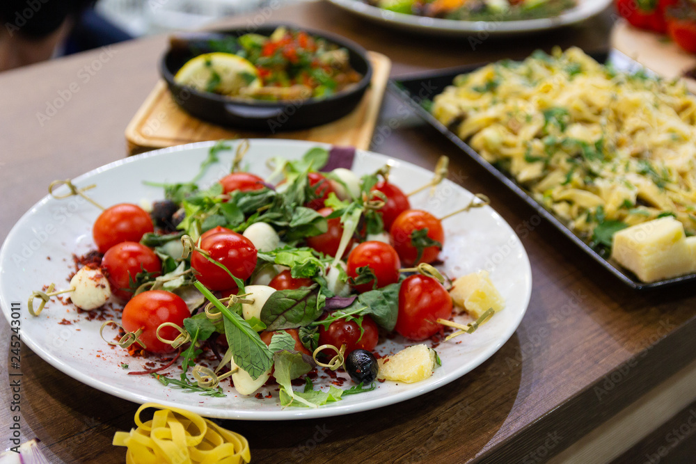 Tomato with greens on a plate served with spaghetti. Food