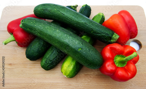 Vegetables on wooden table, zucchini and pepperoni, white background