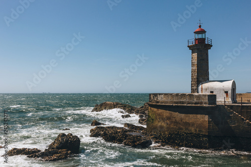 Old lighthouse and granite pier at the mouth of Douro river, Porto