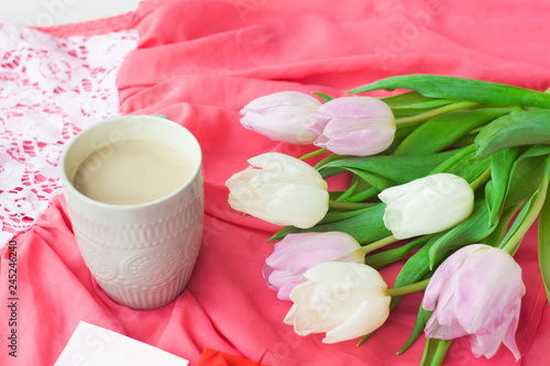 Bouquet of tulips with a mug of coffee and a gift in a red box on a pink cloth. International Women's Day, Valentine's Day, Mother's Day. Selective focus.