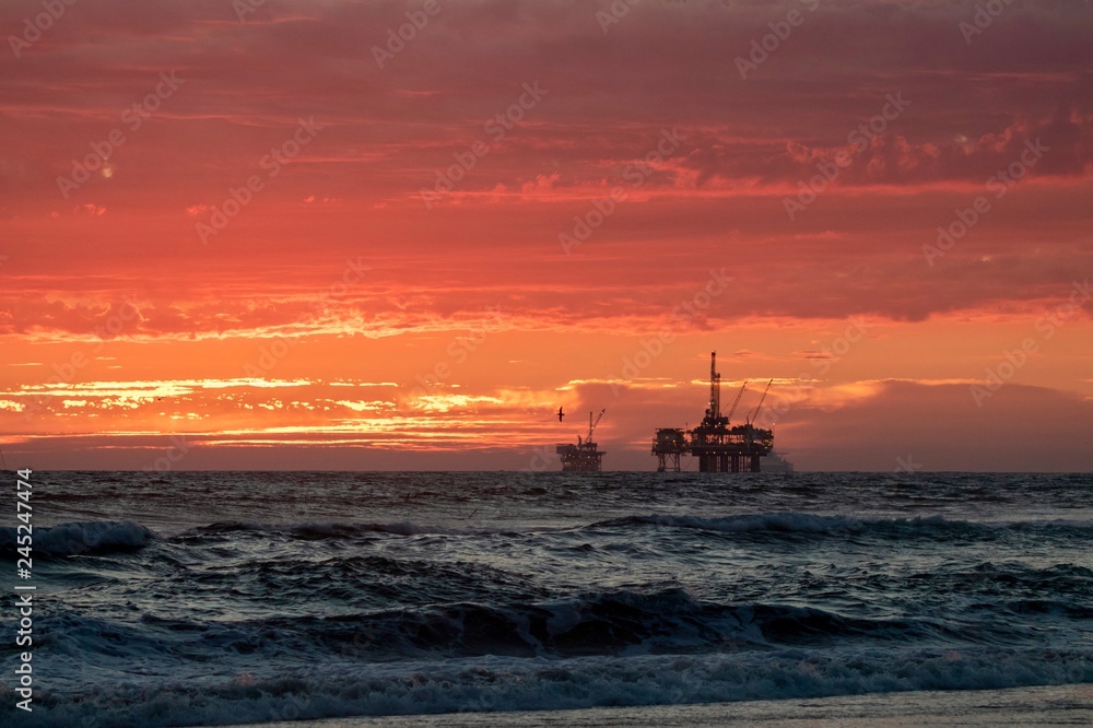 sunset at the beach with oil rig