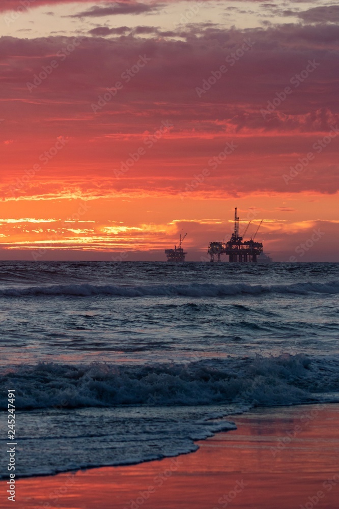 sunset at the beach with oil rig 