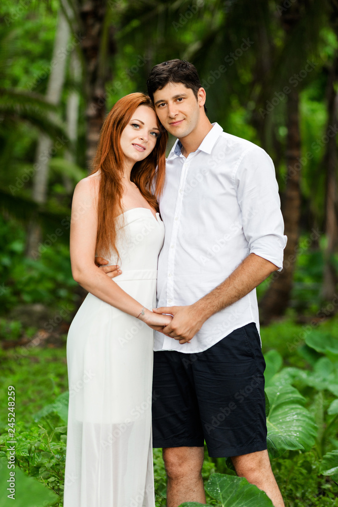 A young couple is embracing against the backdrop of a green rainforest A young couple is embracing against the backdrop of a green rainforest