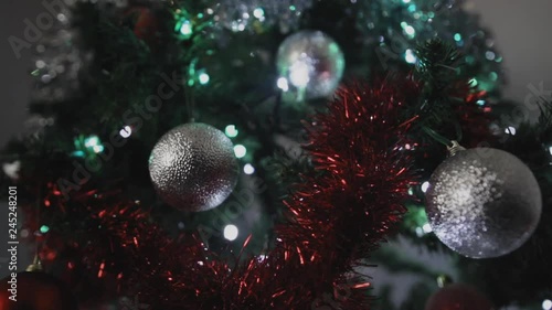 Shot moving towards Christmas tree with silver and red decorations on a slider