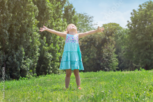Little girl with her arms wide open, in the park; life and nature